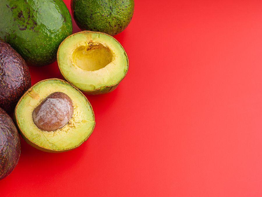 Organic Avocado With Seed, Avocado Halves And Whole Fruits On Red Background. Top View. Green Avocad