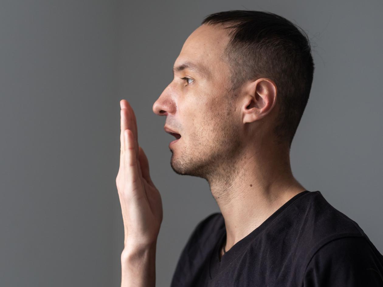 Close Up Of A Good-looking Man Putting His Hand In Front Of His Mouth And Checking His Bad Breath