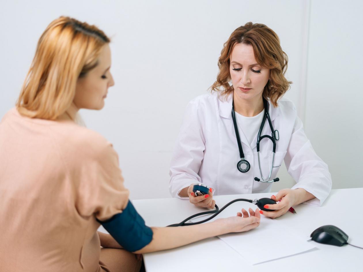 Professional Female Doctor Measuring Young Woman Patient Pulse Pressure By Hands At Hospital Or Medi