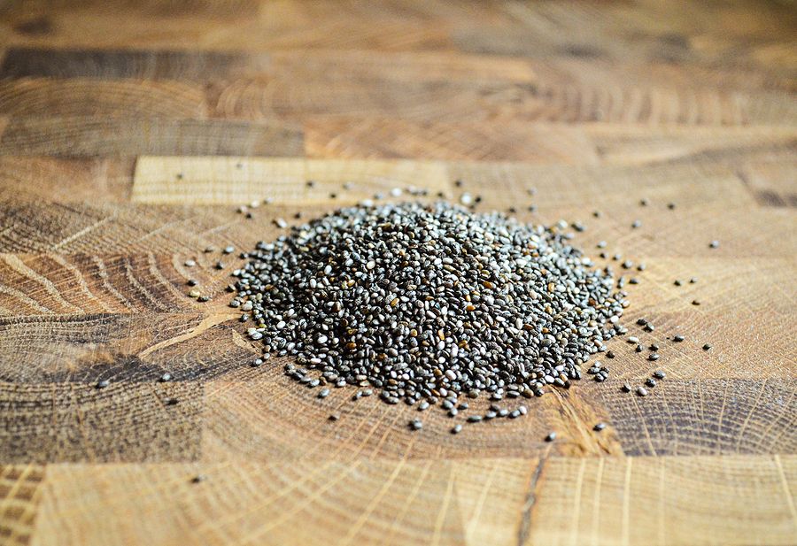 Chia Seeds Are Sprinkled On A Wooden Plank. Close-up Chia Seeds On A Wooden Surface With Copy Space.