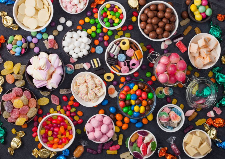 Pink Lollipop Candies In Jar With Various Milk Chocolate And Jelly Gums Candies On Black With Liquor