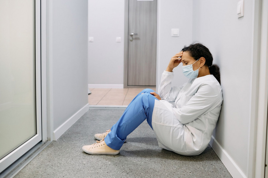 Tired Female Doctor After A Hard Working Day In A Medical Clinic Sits On Floor In Corridor Hospital